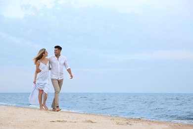 Photo of Happy couple having romantic walk on beach. Space for text
