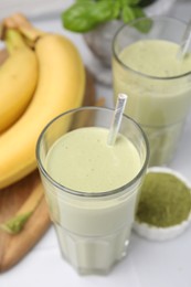 Glasses of tasty matcha smoothie on white table, closeup