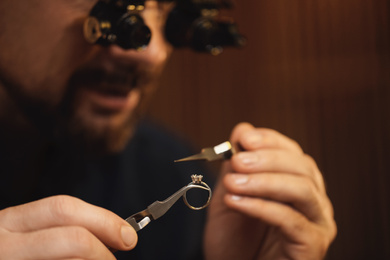 Photo of Jeweler working with ring on blurred background, closeup