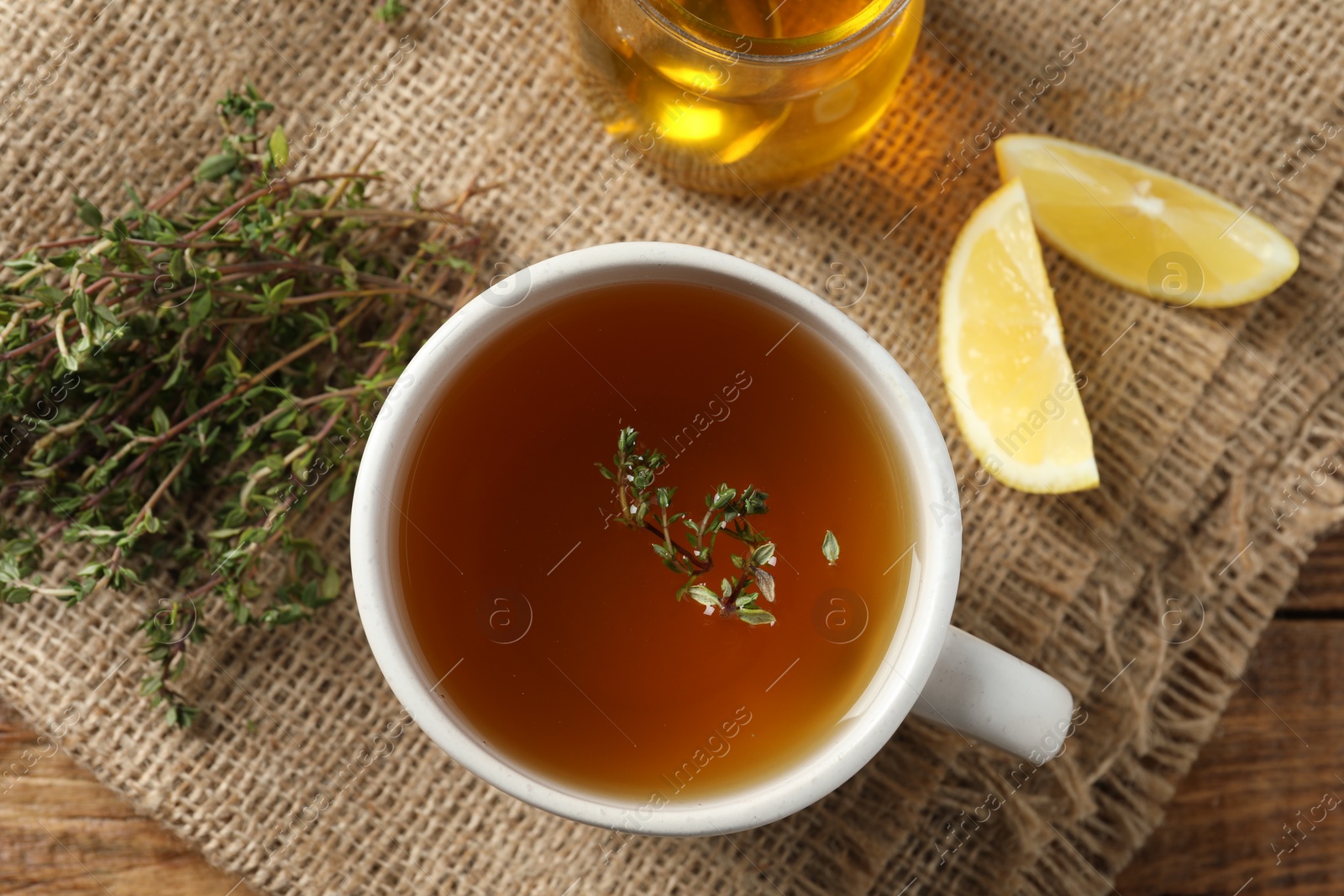 Photo of Aromatic herbal tea with thyme, honey and lemons on wooden table, top view