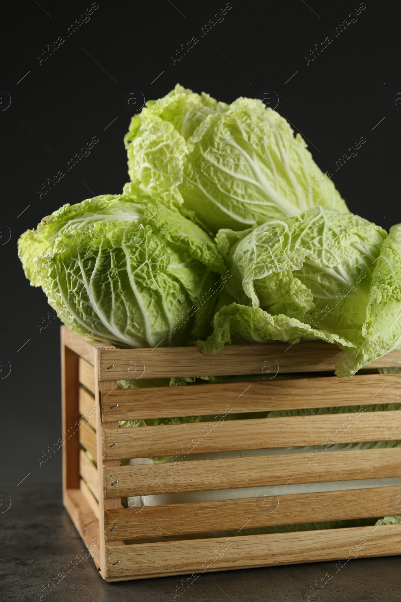 Photo of Fresh ripe Chinese cabbages in wooden crate on grey table