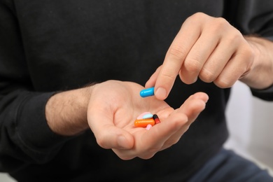 Young man holding different pills, closeup