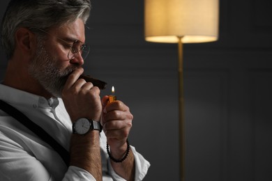 Photo of Bearded man lighting cigar at home. Space for text