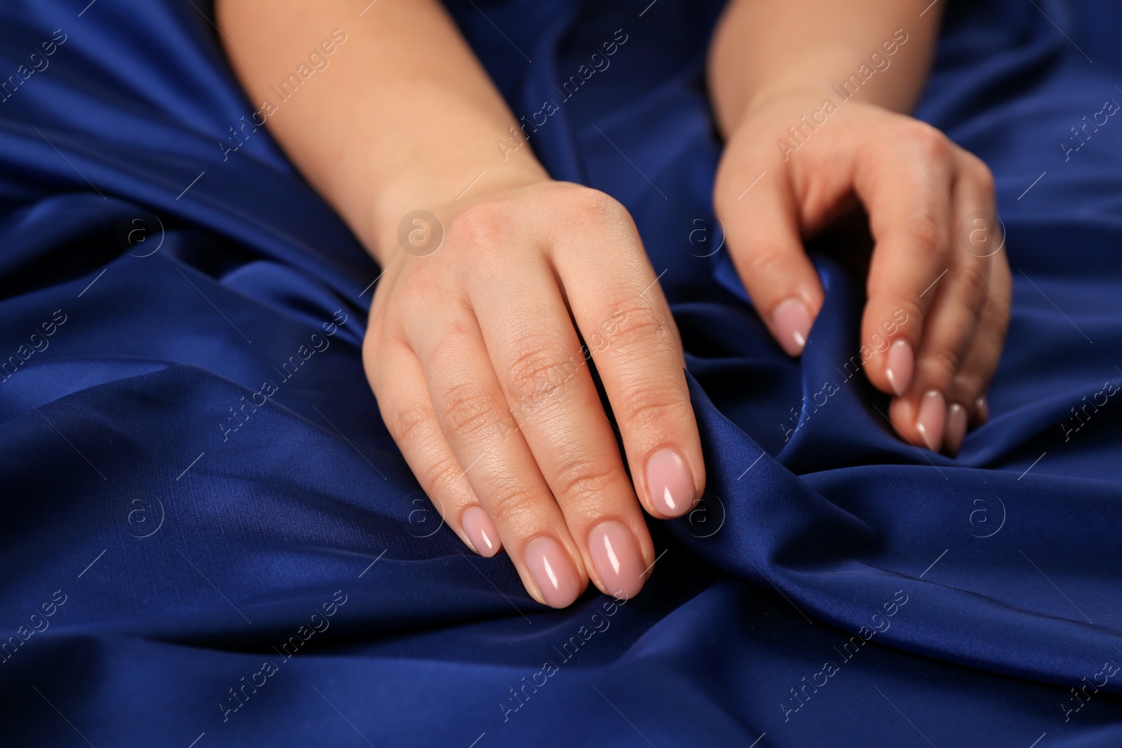 Photo of Woman touching silky blue fabric, closeup view