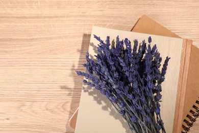 Photo of Bouquet of beautiful preserved lavender flowers and notebooks on wooden table, top view. Space for text