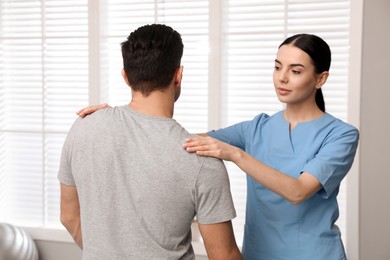 Orthopedist examining man in clinic. Scoliosis treatment