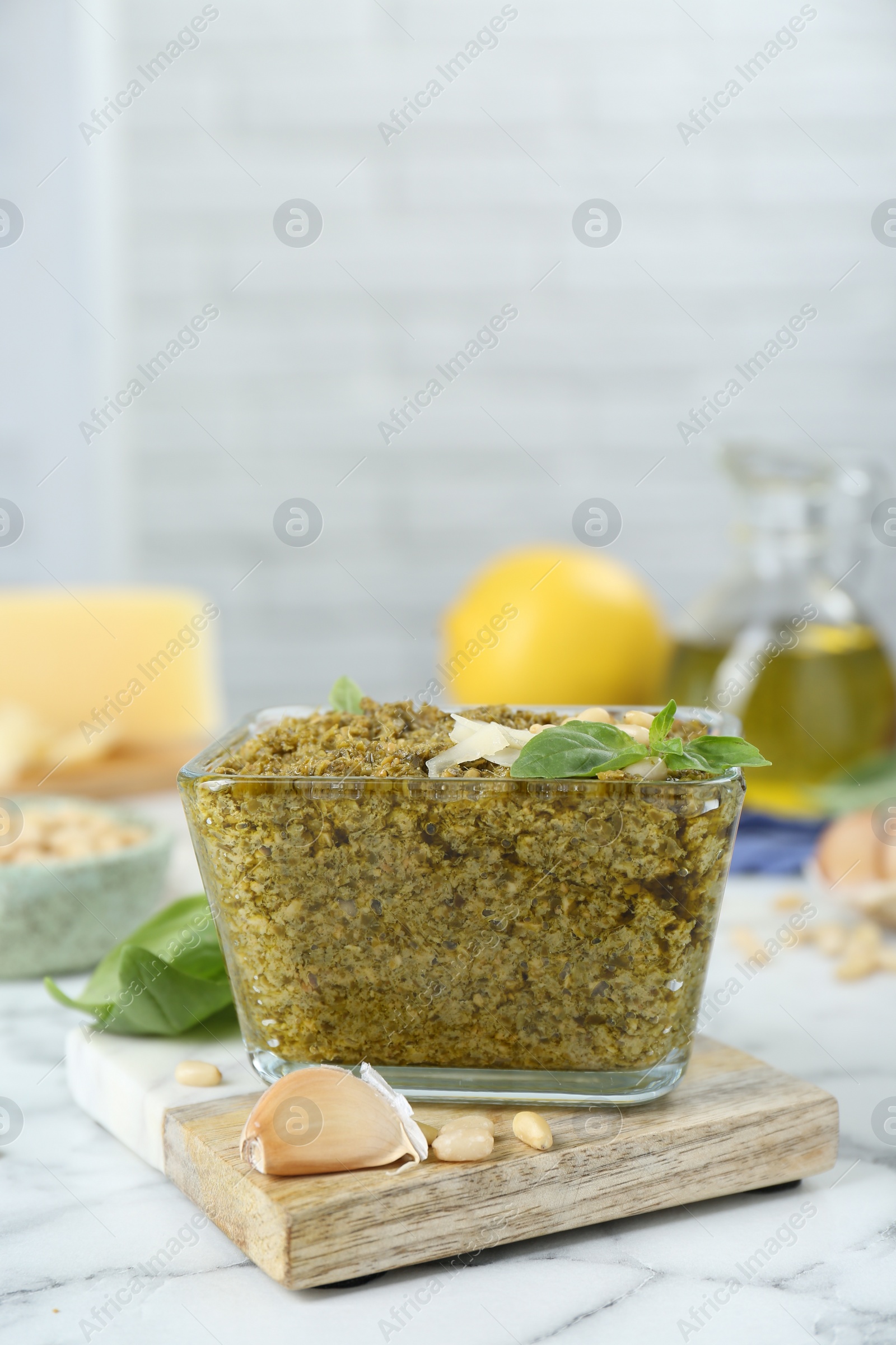 Photo of Delicious pesto sauce and ingredients on white marble table. Space for text