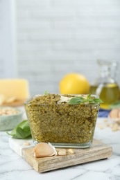 Photo of Delicious pesto sauce and ingredients on white marble table. Space for text