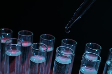 Photo of Dripping reagent into test tube on black background, closeup. Laboratory analysis