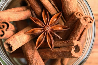 Photo of Bowl with aromatic cinnamon sticks and anise star on table, closeup