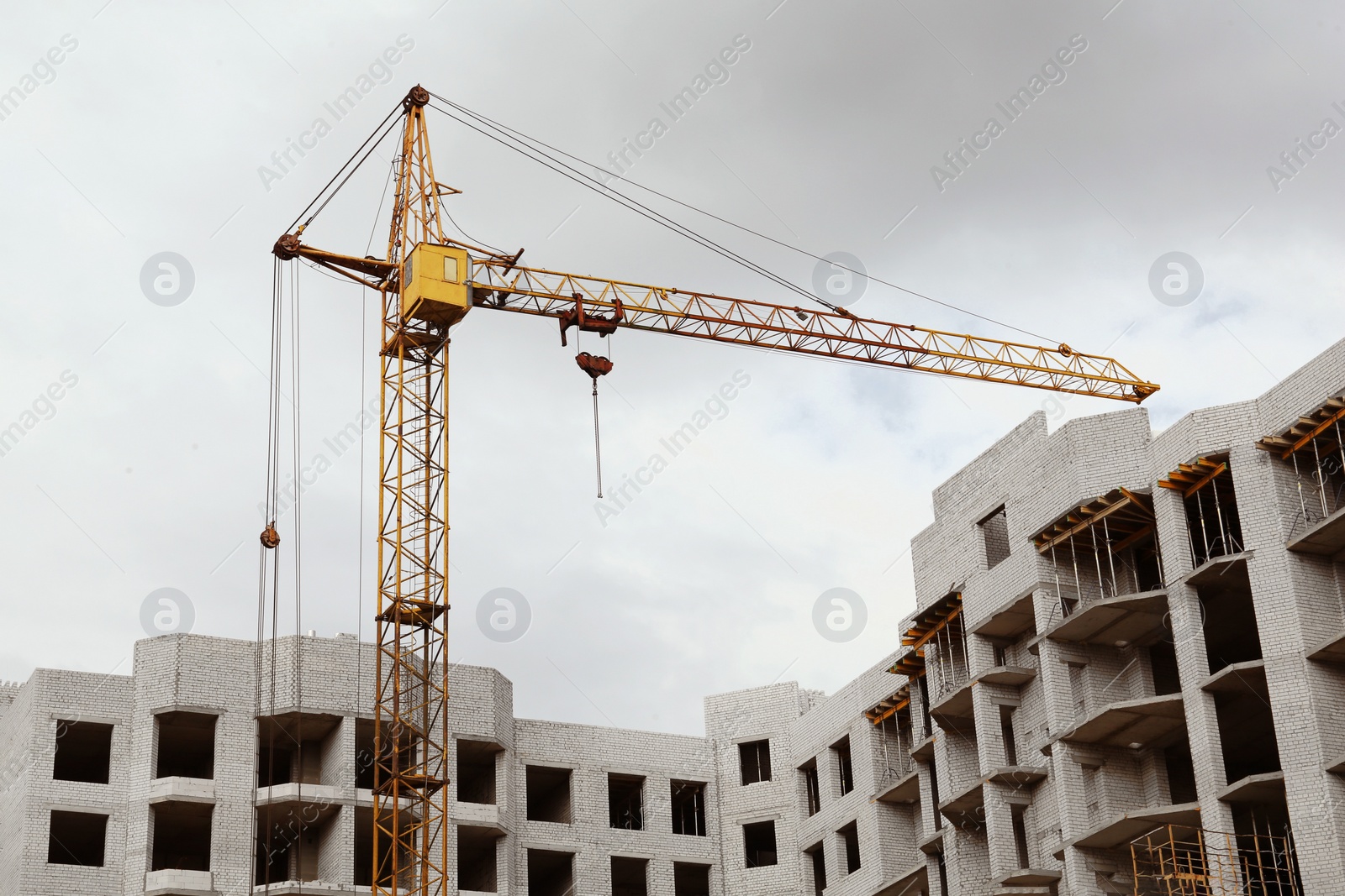 Photo of Construction site with tower crane near unfinished building, low angle view