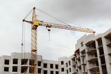 Construction site with tower crane near unfinished building, low angle view