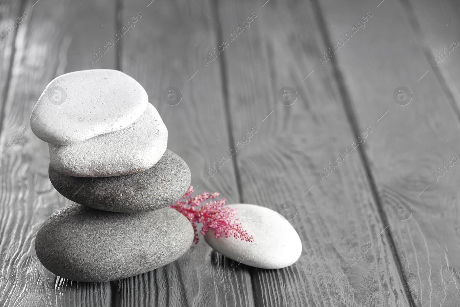 Photo of Spa stones and beautiful flower on wooden table. Space for text