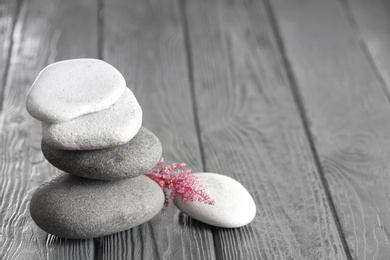 Photo of Spa stones and beautiful flower on wooden table. Space for text