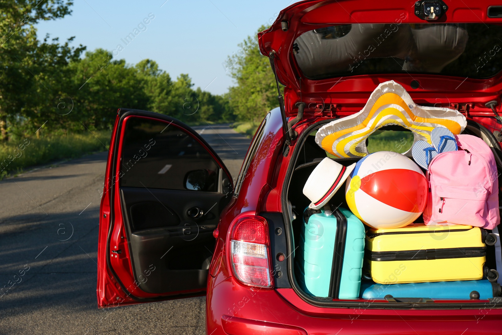 Photo of Family car with open trunk full of luggage on highway