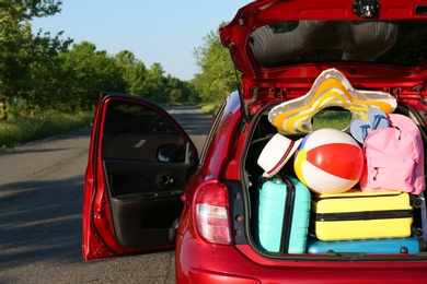 Family car with open trunk full of luggage on highway