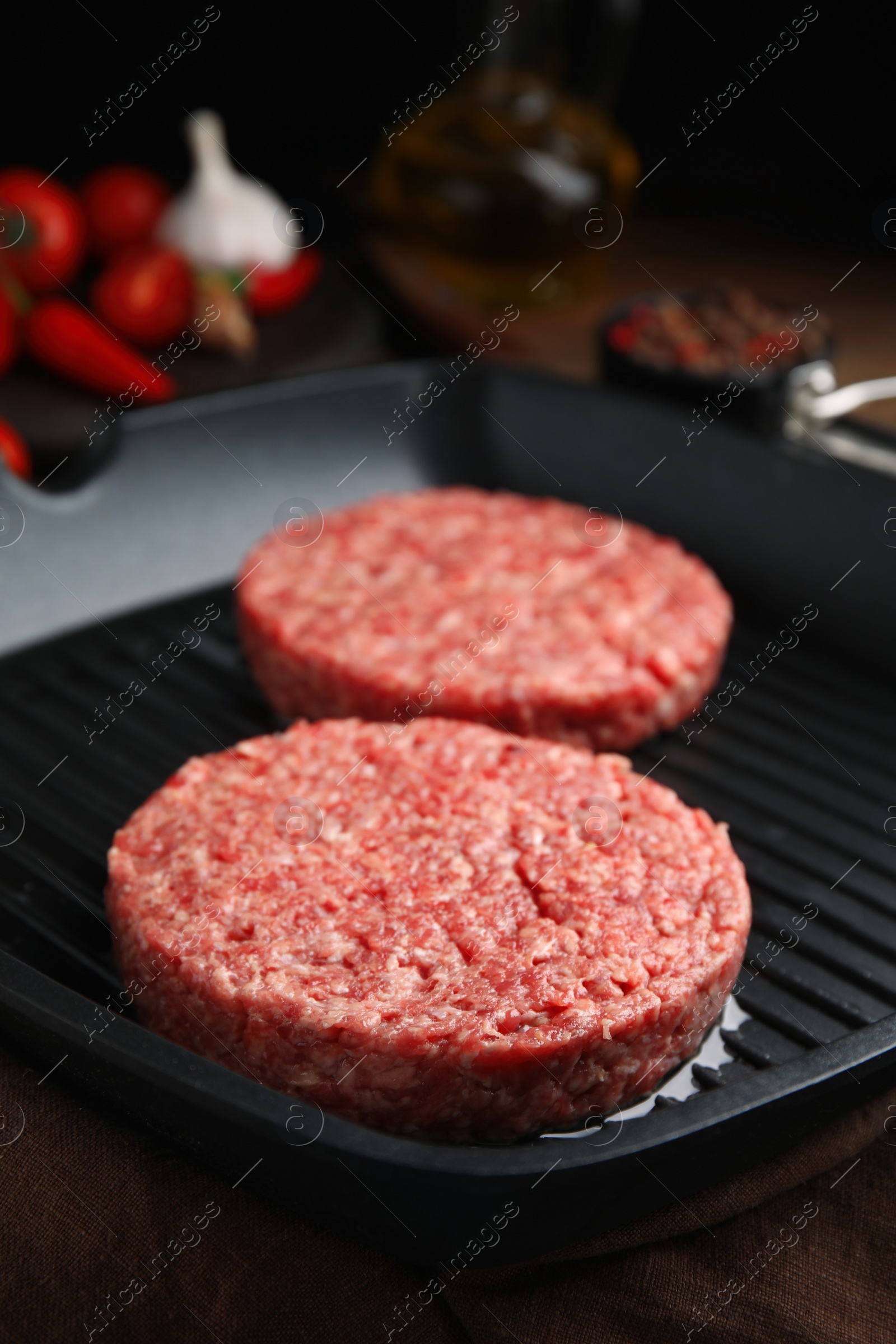 Photo of Raw hamburger patties with oil on grill pan, closeup