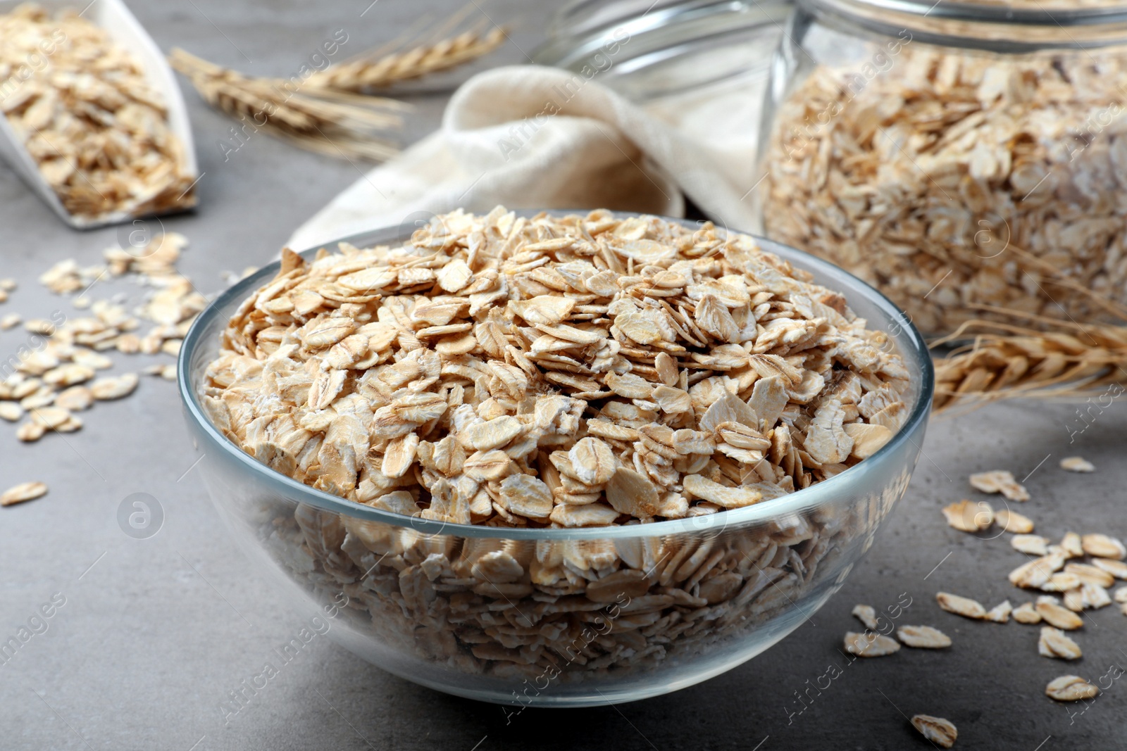 Photo of Glass bowl with oatmeal on grey table, closeup