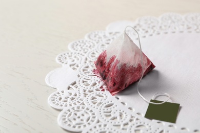 Photo of Used pyramid tea bag on white wooden table, closeup. Space for text