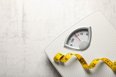 Photo of Weigh scales and measuring tape on white textured background, top view with space for text. Overweight concept