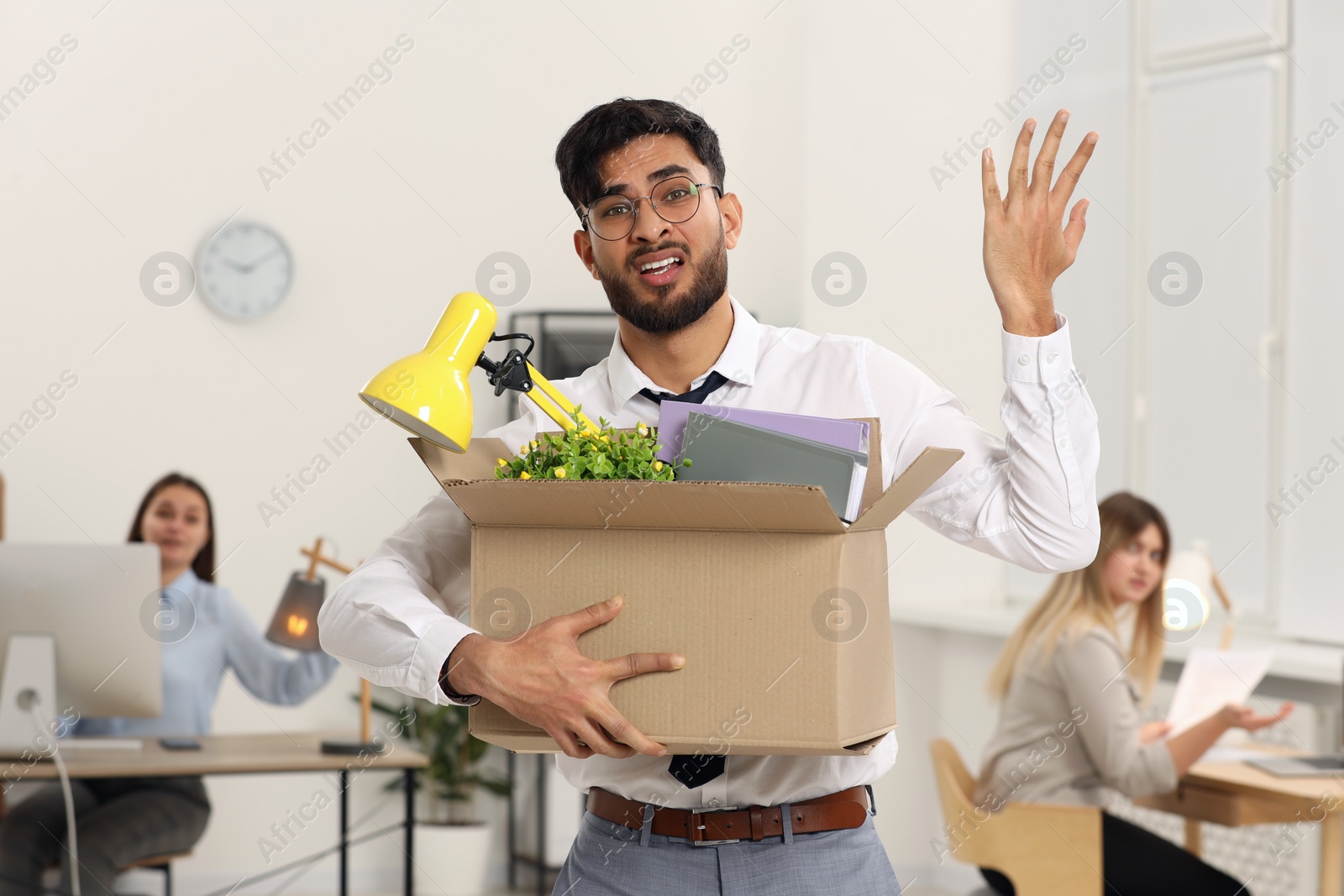 Photo of Unemployment problem. Frustrated man with box of personal belongings in office