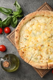 Delicious cheese pizza and ingredients on dark grey table, flat lay