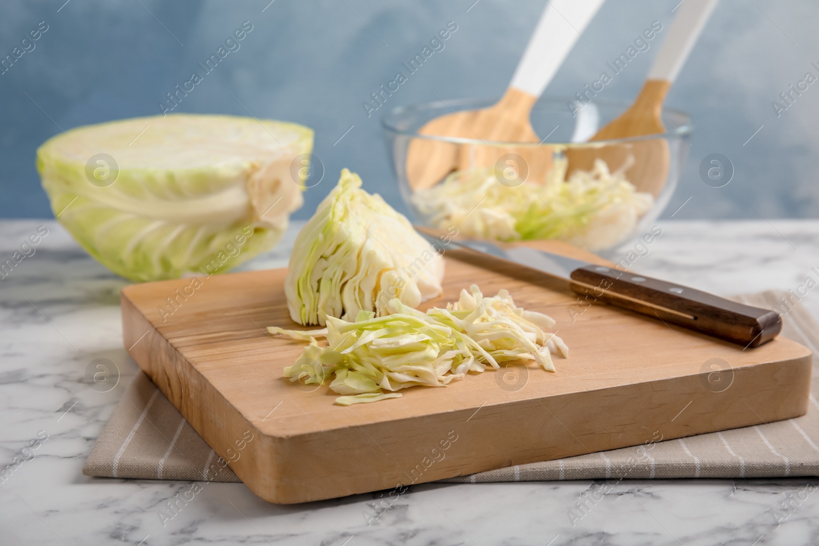 Photo of Wooden board with cut cabbage on table