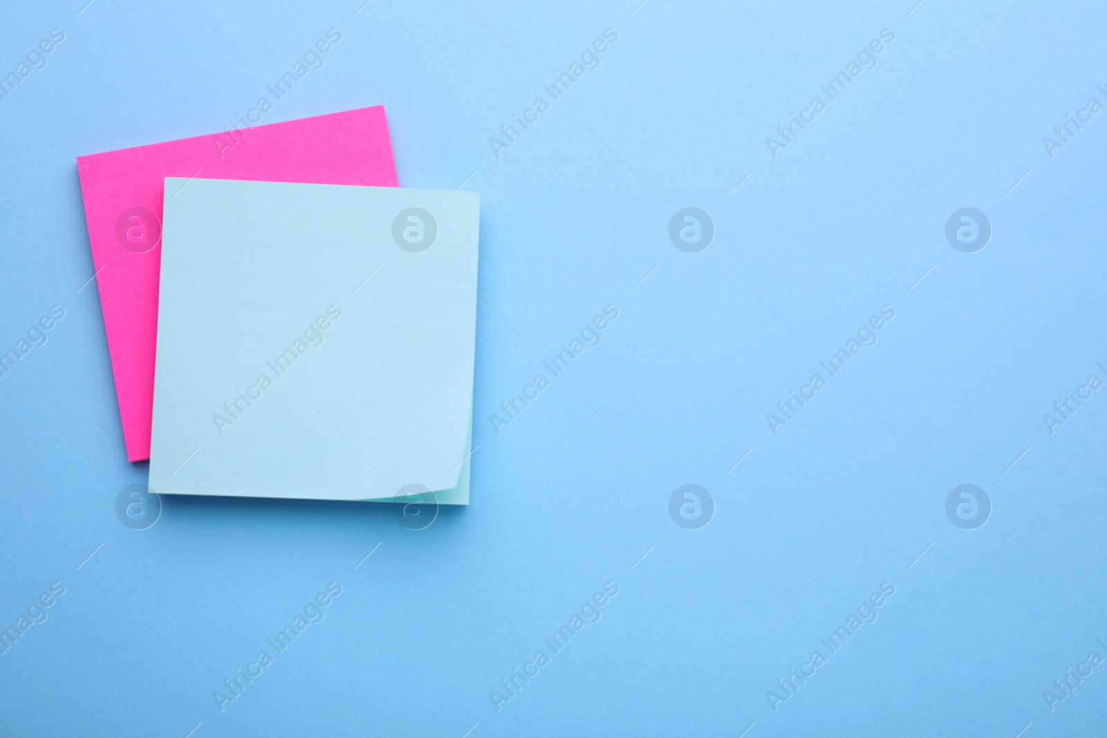 Photo of Paper notes on light blue background, top view. Space for text