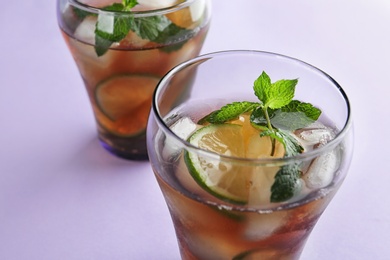 Photo of Glasses of refreshing iced tea on lilac background, closeup