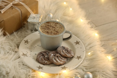 Photo of Tasty hot drink, cookies, gift and Christmas lights on fur