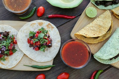 Delicious tacos and ingredients on wooden table, flat lay. Mexican food