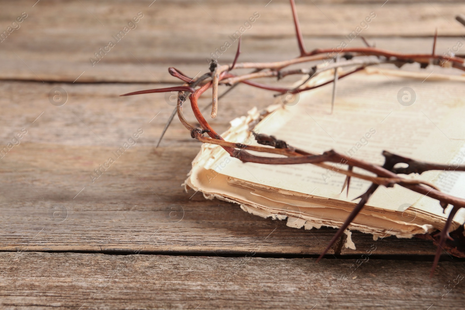 Photo of Crown of thorns and Bible on wooden table, closeup. Space for text