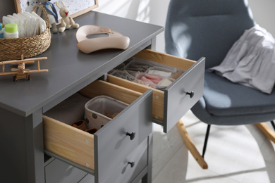 Photo of Open cabinet drawers with clothes and different items in child room