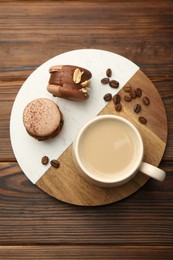 Photo of Cup of coffee and delicious macarons on wooden table, top view