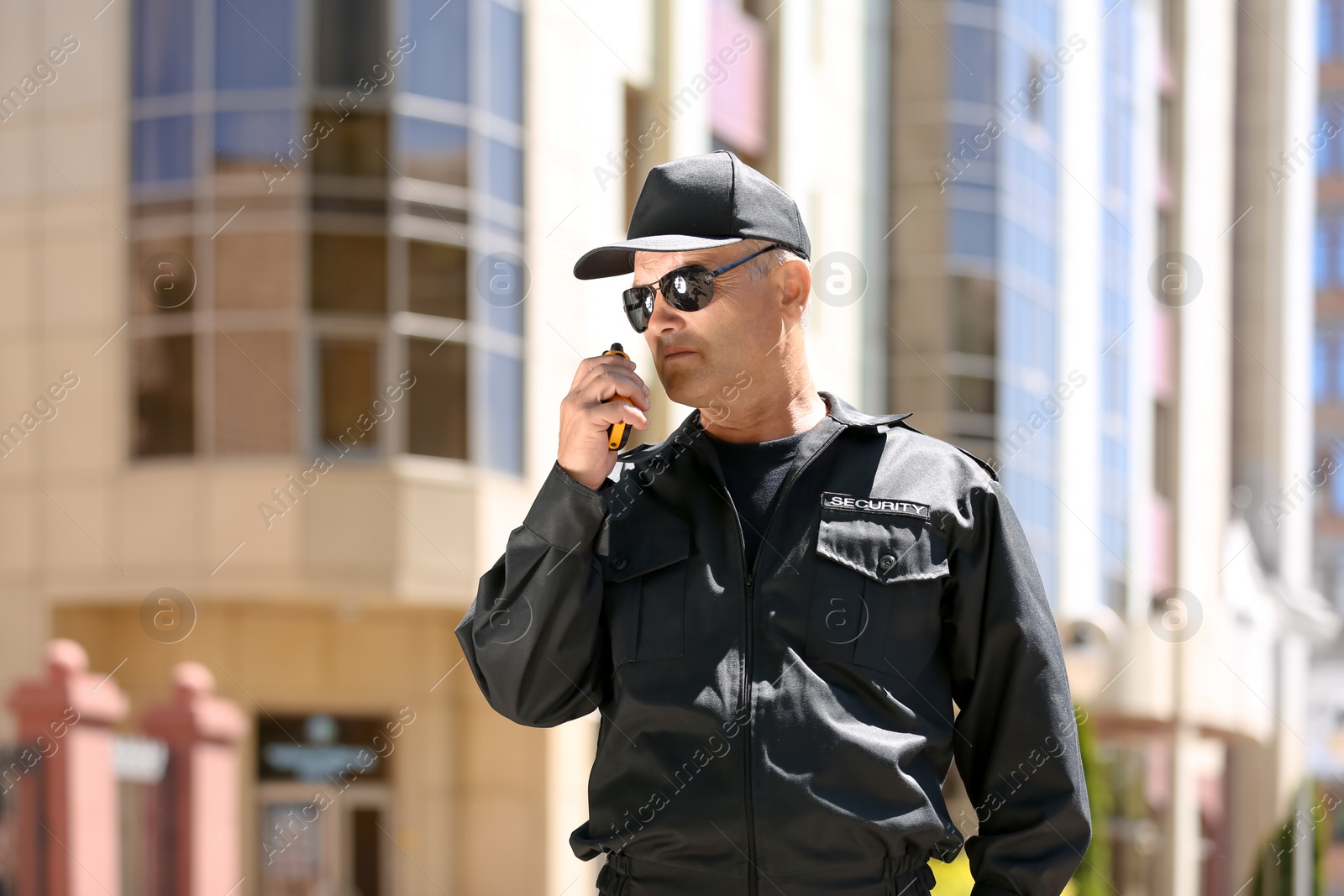 Photo of Male security guard using portable radio transmitter outdoors