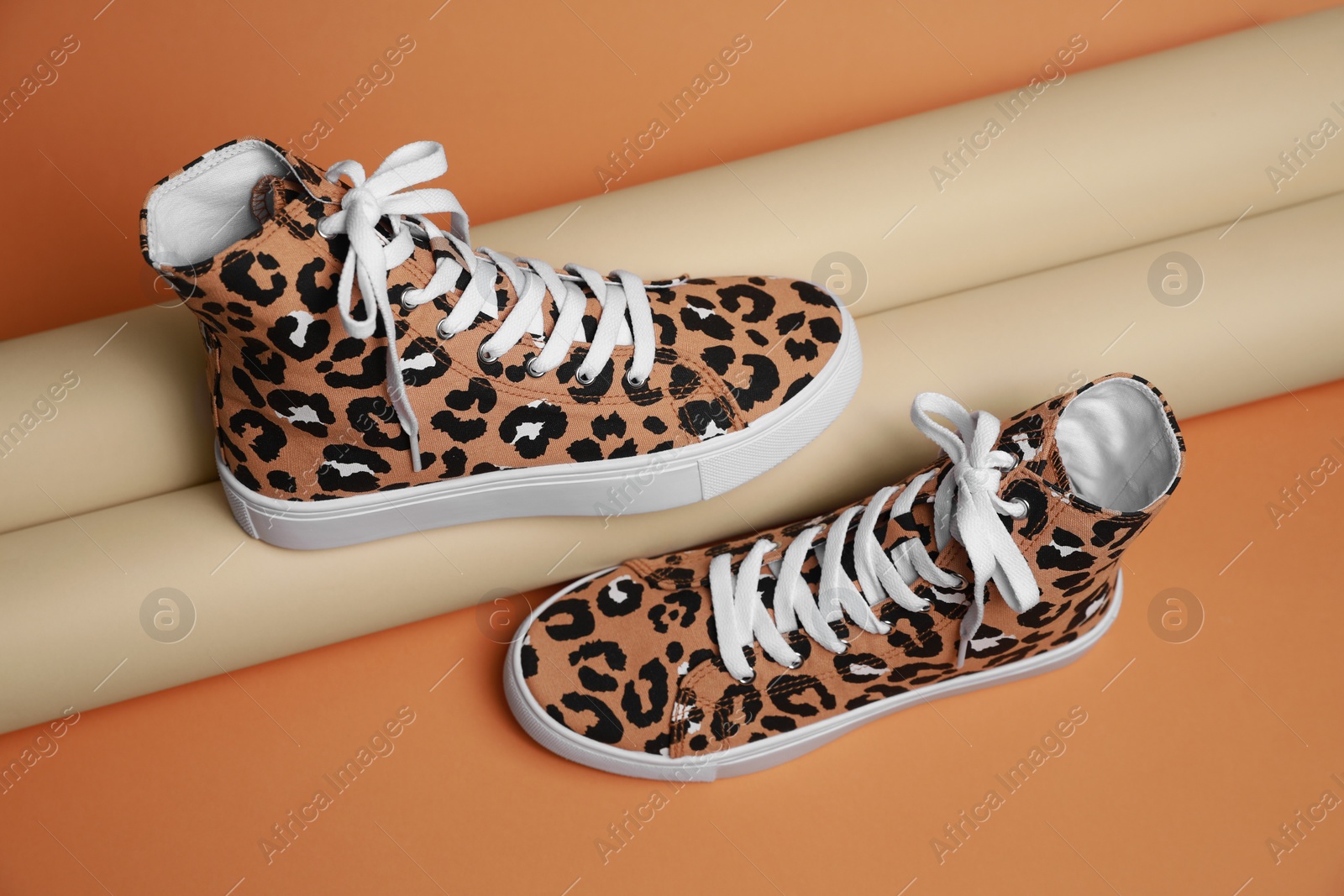 Photo of Stylish presentation of classic old school sneakers on pale orange background