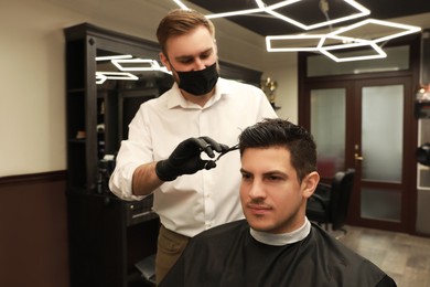 Photo of Professional hairdresser making stylish haircut in salon