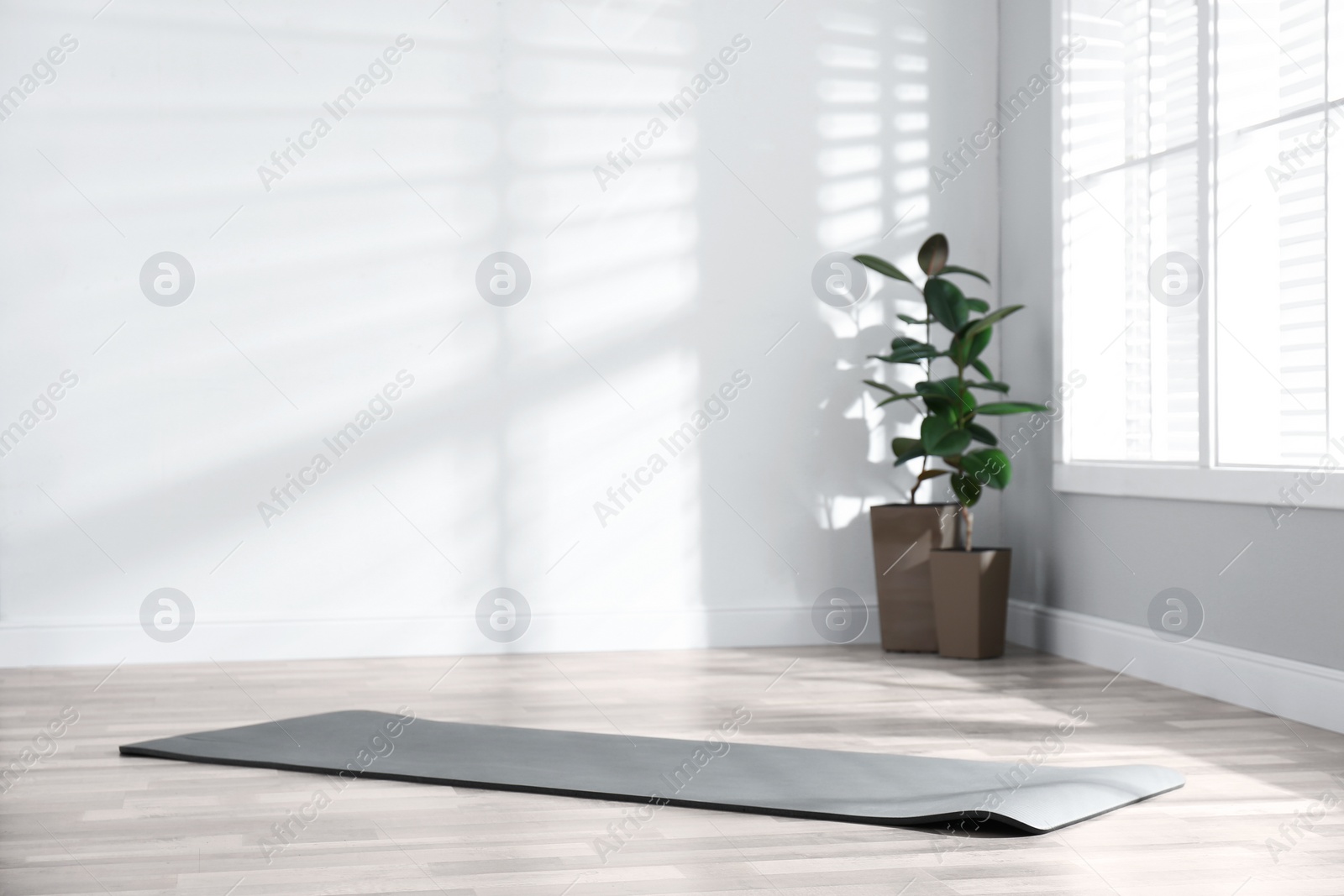 Photo of Unrolled grey yoga mat on floor in room