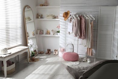 Rack with different stylish clothes, shoes and decorative elements in dressing room. Interior design