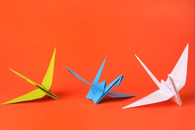 Photo of Colorful paper origami cranes on orange background