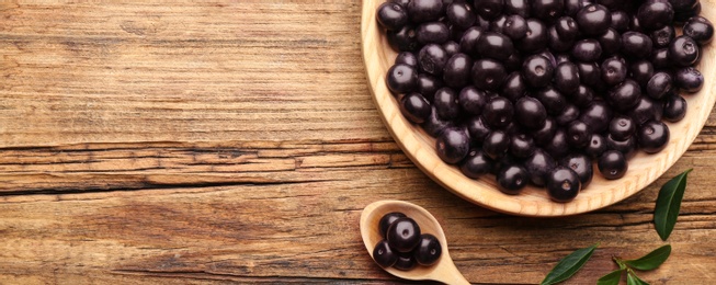 Photo of Fresh acai berries on wooden table, flat lay. Space for text