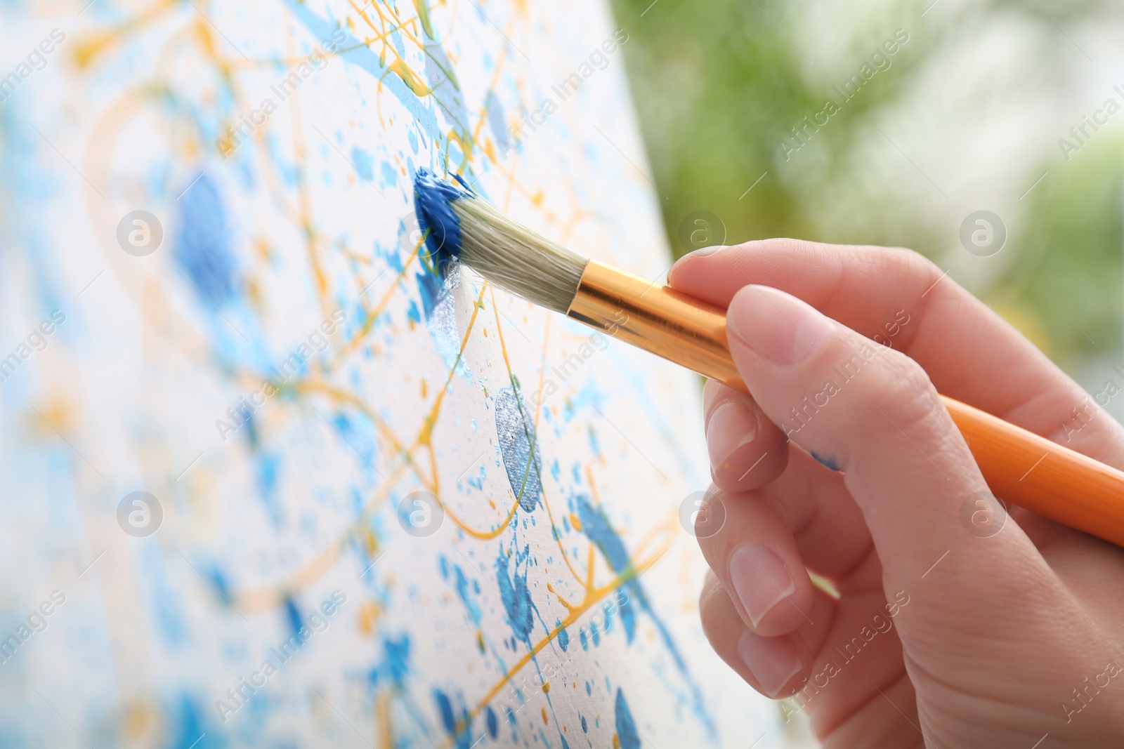 Photo of Artist painting on canvas with brush, closeup