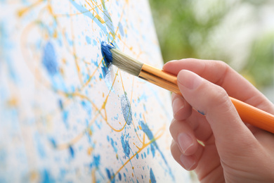 Photo of Artist painting on canvas with brush, closeup