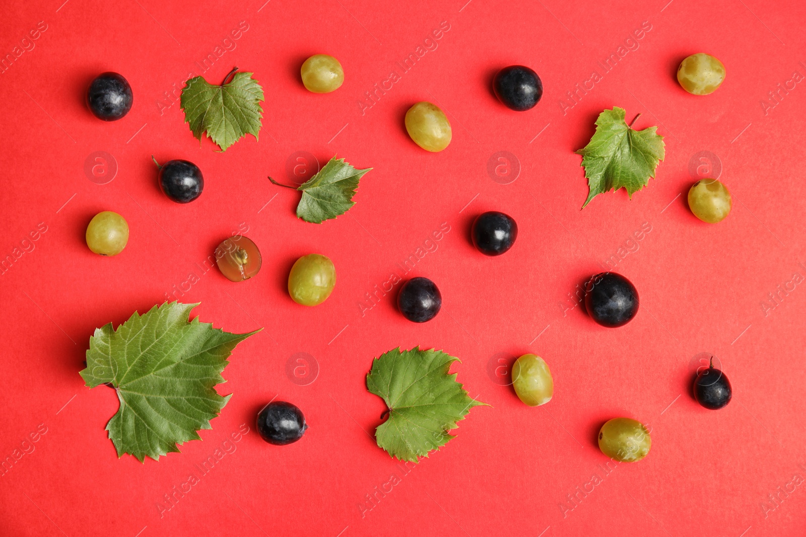 Photo of Fresh ripe juicy grapes and leaves scattered on color background, top view