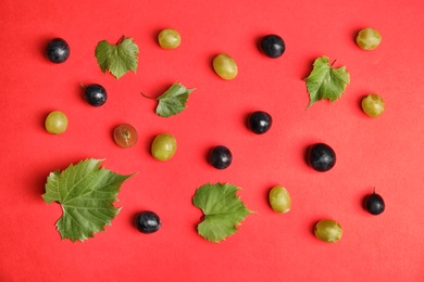 Photo of Fresh ripe juicy grapes and leaves scattered on color background, top view