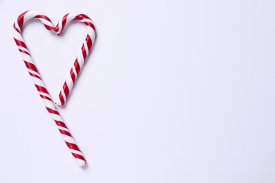 Photo of Heart shape made of candy canes on white background, top view