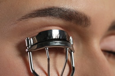 Closeup view of woman using eyelash curler