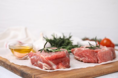 Photo of Fresh raw meat with rosemary on wooden board, closeup