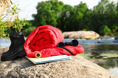 Rolled sleeping bag and other camping gear outdoors on sunny day