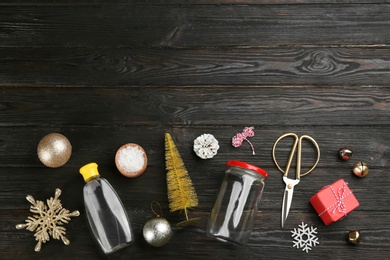 Instruments and materials for snow globe on black wooden table, flat lay. Space for text